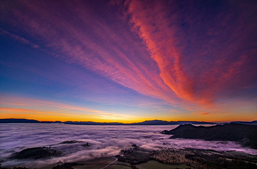 "Lenticulares y nieblas al amanecer"

El amanecer visto desde el gran mirador de la Plana de Vic, el Roc Llarg, con las habituales nieblas cubriendo el valle y unas largas nubes lenticulares verticales con tonos rojizos.
