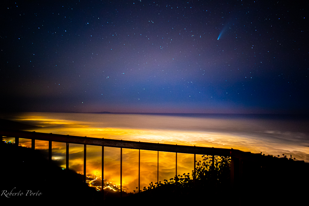 un balcon con vistas
desde el mirador d e Ayosa, Teneerife, a. los pies el mar de nubes iluminado por  las poblaciones del Valle de la Orotava. En el cielo,el comea Neowise

