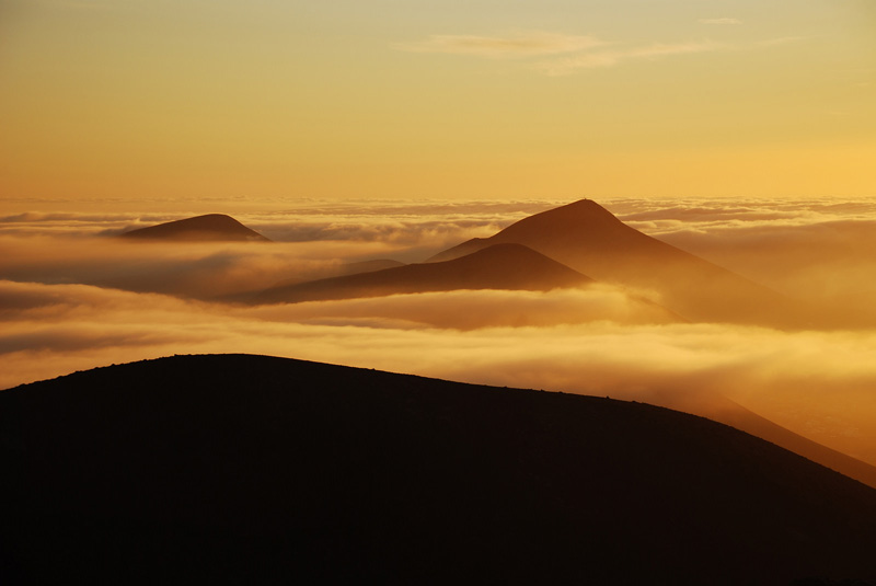 Mar de nubes al amanecer
El mar de nubes, al amanecer, desde el Volcán de Guardilama: la inversión está más alta y las nubes no corren tan pegadas al suelo. La niebla está hoy en las laderas de los volcanes. No deja de ser una imagen sorprendente en la isla más baja de las Canarias, sin elevaciones que alcancen los 700 msnm.

