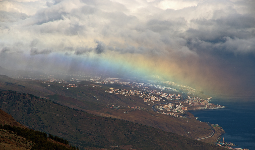 Arcoíris en llovizna
Las nubes empujadas por los vientos alisios superaron la dorsal de Anaga, en Tenerife, y descargaron algunas lloviznas a sotavento, formándose un curioso arcoíris que se veía desde Izaña, a unos 20 Km de distancia.
