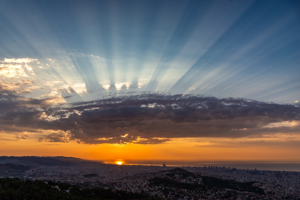 Durante la salida del Sol del dia 7 de agosto una capa de altocumuls castellanus oculta temporalmente el Sol y a través de sus "almenas" se crean estos rayos crepusculares. Se distingue también la sombra alargada de las almenas proyectada sobre una capa de nues altas.
