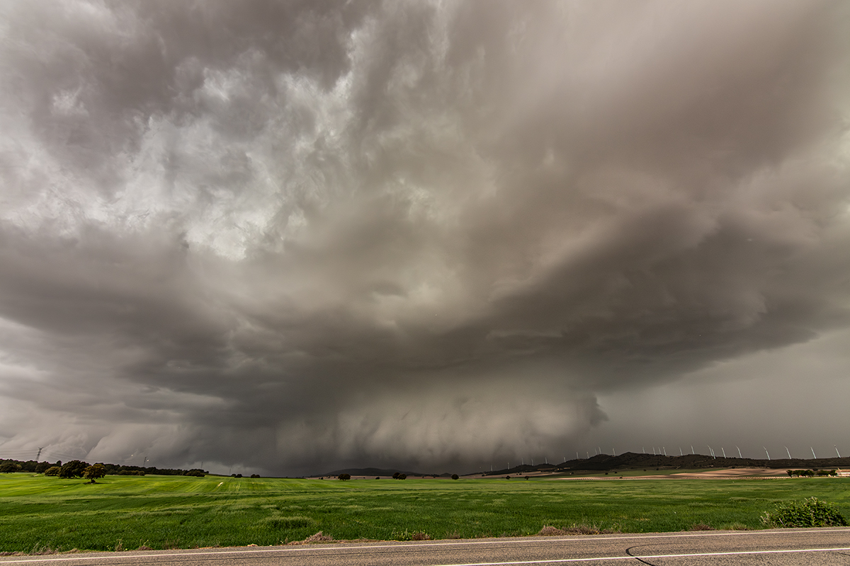Supercélula con extensa tail cloud y wall-cloud a ras de suelo, con estructura superior en estantería.
