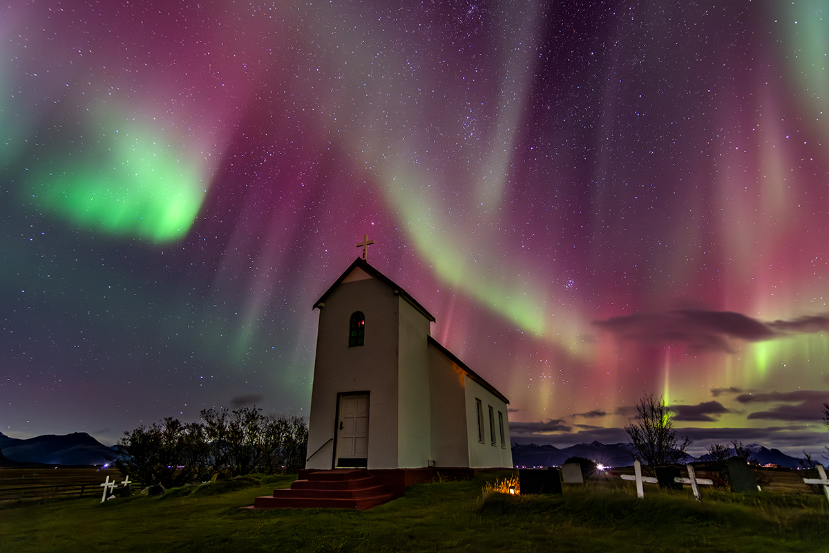 Aurora Boreal en Islandia, sobre una iglesia y su cementerio.
