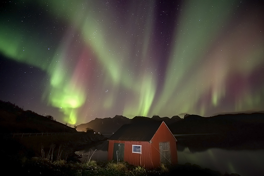 Según Wikipedia el Rorbu es una casa típica utilizada por los pescadores noruegos ubicados en las zonas costeras del norte y de las islas Lofoten, construida en madera sobre pilotes y típicamente pintada de rojo y aunque ésta es más pequeña de lo normal y apoyada sobre las rocas no podía dejar pasar la ocasión de fotografiarla con las auroras sobre el cielo.
