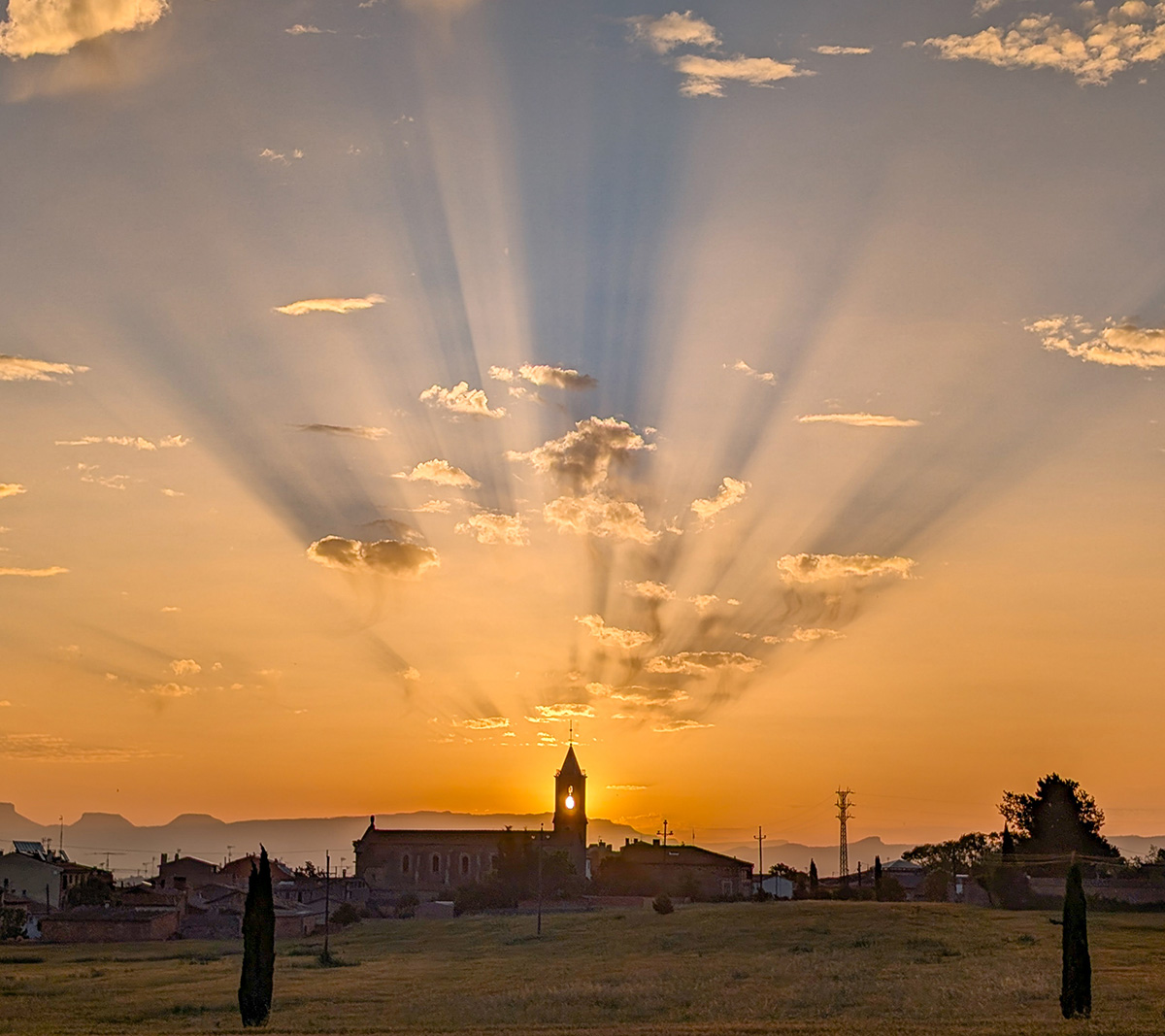 Sale el sol y proyecta la sombra de las nubes en un amanecer con unos espectaculares rayos crepusculares, busqué la posición para que el sol saliera entre las campanas de campanario de la iglesia de Sentfores, 19 de junio de 2024 en un núcleo de población agregado al municipio de Vic.
