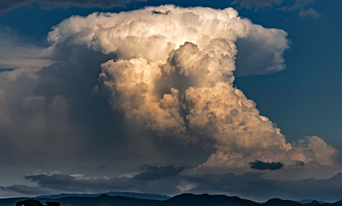 Una nube cumulonimbo con una extraña forma, como con un sombrero o una gorra al revés, la nube era espectacular pero la lluvia dejó mucho que desear. las luces del atardecer destacaban partes del cumulonimbo, imagen capturada el 22 de junio de 2023 en Gurb.
