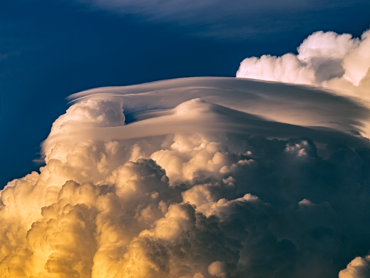 Una bella nube cumulonimbo se observaba desde casa a la lejanía el día 29 de julio de 2023 y lo que me llamó la atención eran estos sombreros pileus cambiantes, que con las luces del sol bajo del atardecer destacaban.
