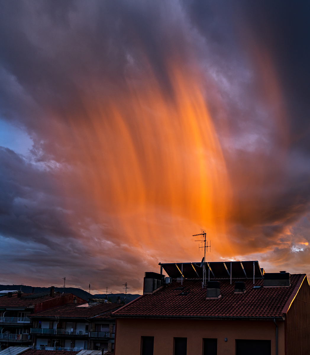 Después de una tarde lluviosa salió el sol al atardecer dejando un bello candilazo, pero lo que me llamó la atención fue esta ligera cortina de lluvia a contraluz peinada por el viento, la imagen la capturé desde la azotea de casa el 9 de junio de 2023 en Vic.


