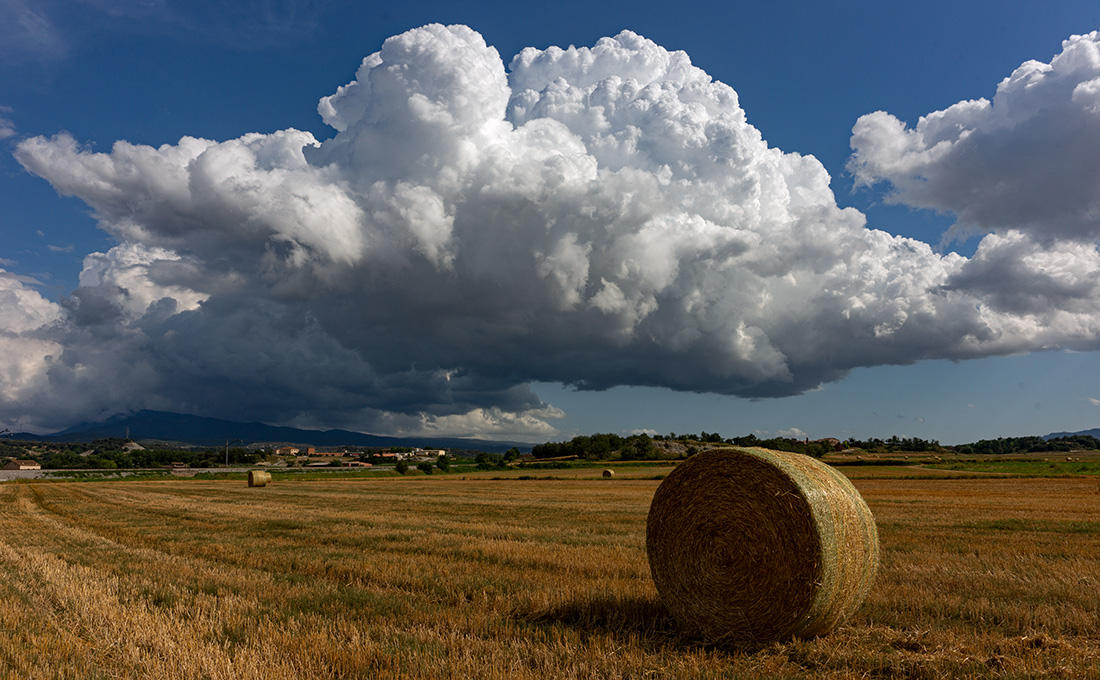 Una potente nube cumulonimbo salía del monte Montseny, la lluvia era lejana pero esta nube por su forma y extendiéndose hasta la derecha de la imagen daba la sensación de profundidad, una profundidad que quizás conseguí aumentarla incluyendo la alpaca de paja en el encuadre.
