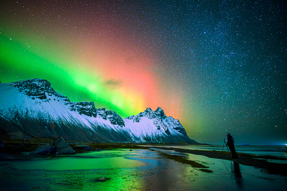 Aurora y fotógrafo en Stokkness
fotografiando la espectacular aurora boreal roja y  verde  en Stokknes ,Islandia
