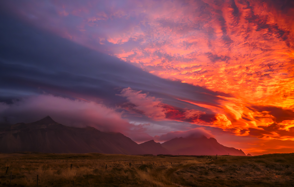 un amanecer con arrebol y nubes lenticulares  que proyectan su propia sombra en el cielo y la montaña  de Stokkness
