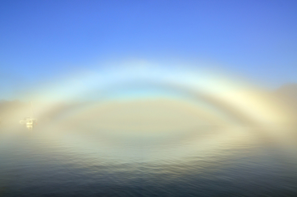 Nos mira el tiempo
Arco de niebla reflejado en el agua.
