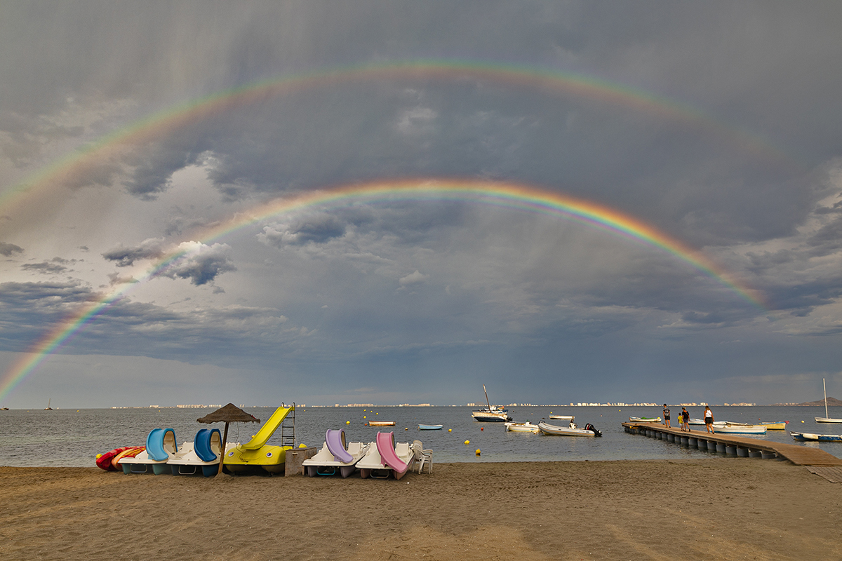 A diferencia de otras comarcas de la región de Murcia, el 14 de agosto apenas llovió en el Mar Menor; una llovizna que fue suficiente para que antes del crepúsculo se formase este hermoso arco iris doble, que como en todos los de esta especie, el orden de los colores se invierte en uno con respecto al otro. También destaca la policromía de los barcos de recreo, a juego con el fenómeno.
