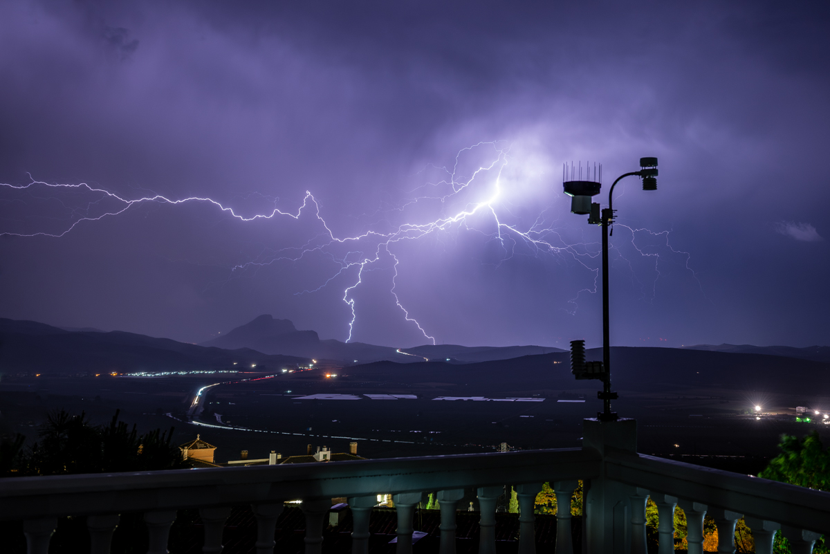 Durante la tarde del 23 de mayo, se desarrollaron buenas tormentas en el interior andaluz con desplazamiento norte-sur, por lo que no le quitaba ojo a lo que bajaba por el sur de Córdoba. Y por suerte, los núcleos tormentosos aguantaron hasta el anochecer para venir a morir al norte de la provincia malagueña. Resguardándome de la lluvia bajo el marco de la puerta de la terraza, puse la cámara mirando al oeste por si había suerte, y oye, me quedó un encuadre "muy meteo" con mi estación como co-protagonista.
