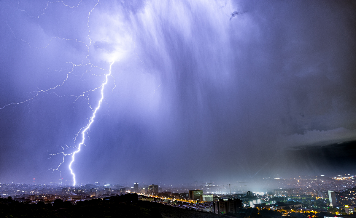 La temporada de tormentas veraniegas empieza bien. Un enorme rayo cae sobre la ciudad de Barcelona y una de sus ramificaciones impacta en la grúa de la Sagrada Familia. Su potente destello ilumina la intensa cortina de lluvia que cae sobre la ciudad
