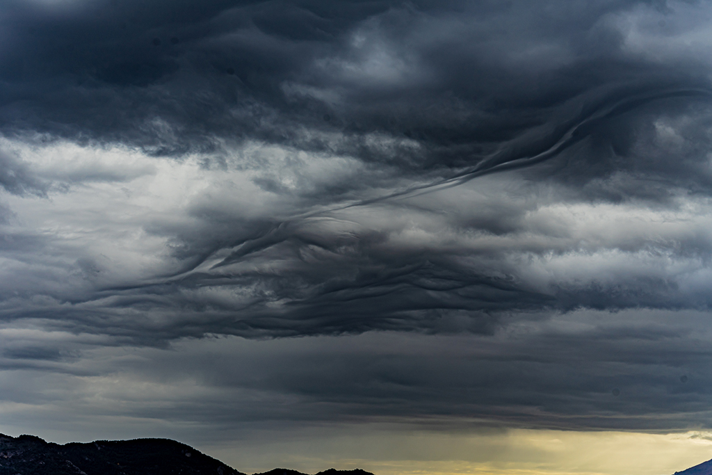 Cielo cubierto por nubes negras que tienen formas abstractas, similares a fantasmas. Estas nubes parecen moverse y cambiar constantemente.
