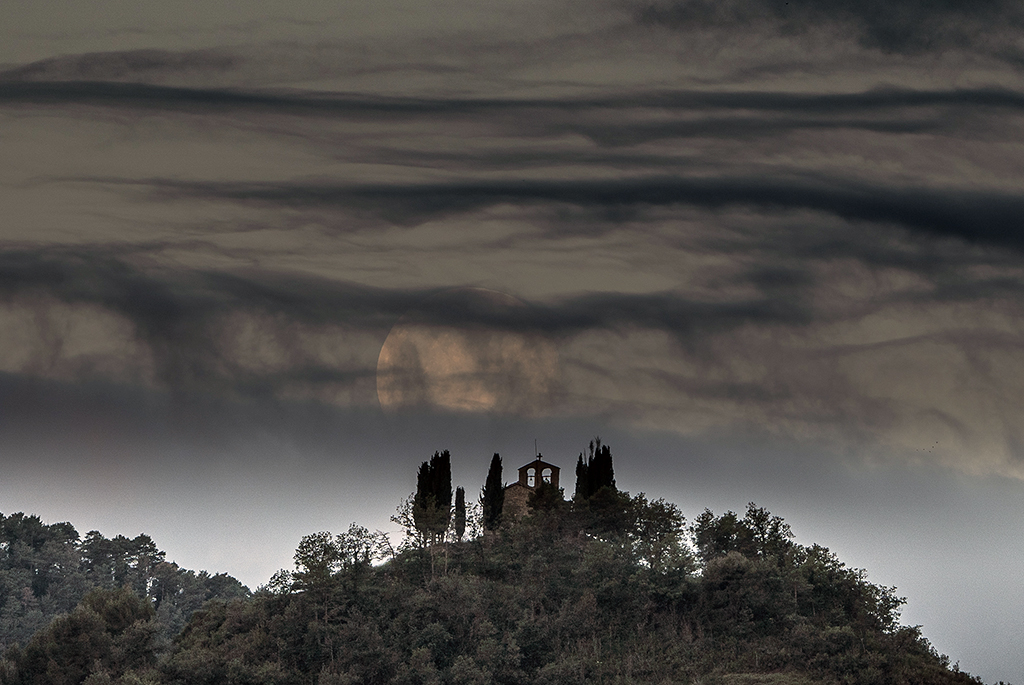 Las escurridizas nubes fantasma, aspecto cambiante, un tipo de nubes exóticas junto a la luna llena que se va enredando entre las nubes hasta desaparecer, en la bucólica ermita de Santa Perpétua de Vespella
