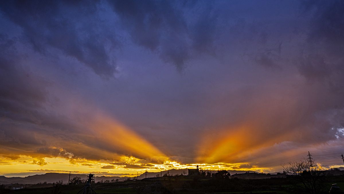  Pilares de luz solar, fluyendo hacia arriba desde el horizonte detrás de la ermita de Sant Jaume.
