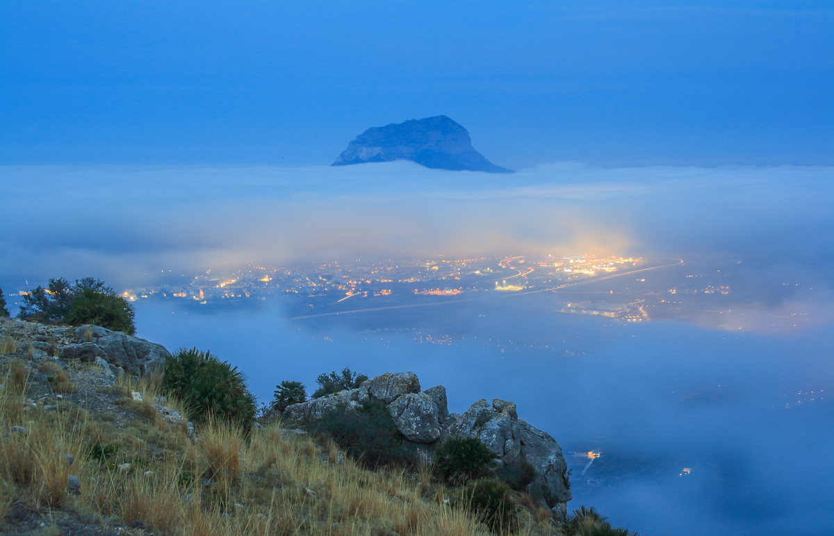 Esta foto enfoca desde la Sierra de Segaria hacia el Montgó; detrás está el mar, de donde procedían las potentes nieblas de advección que se dieron ese día, reconvertidas casi en bancos de nubes bajas. Un espectáculo para mí inédito en esta zona, lo habitual es que se adentren como mucho 1 ó 2 km, ese día llegaron a pueblos situados a más de 15 km de la costa.
