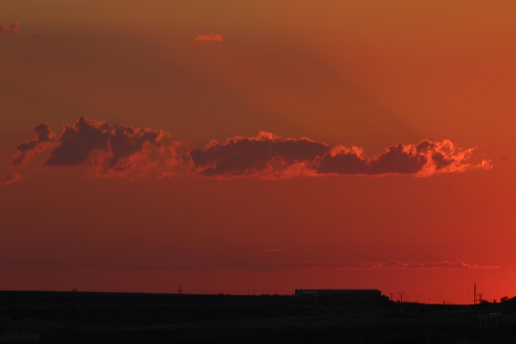 Nube solitaria incandescente propiciada por el sol escondiéndose en el horizonte en ese momento. Atardecer captado desde un bonito mirador en un cerro de Salamanca 
