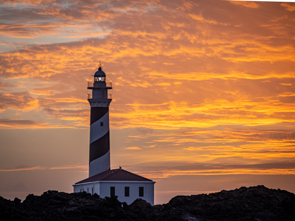 Foto de detalle del faro con las nubes coloreadas durante el amanecer
