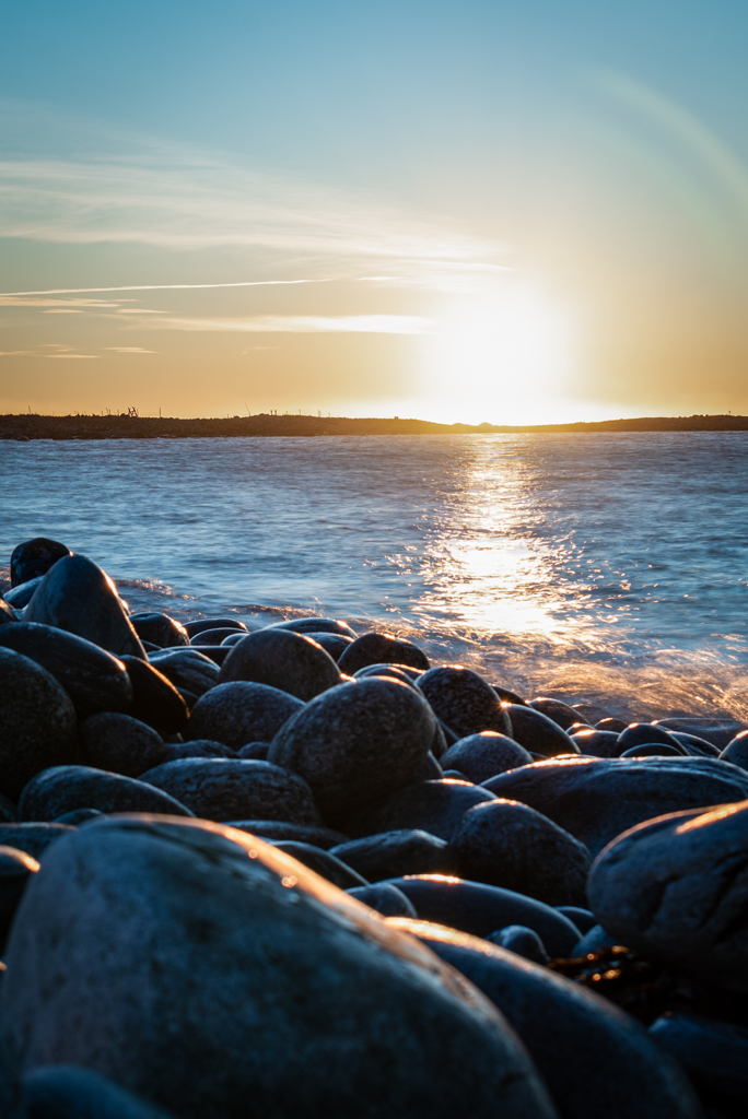 Puesta de sol en una playa formada por cantos rodados de gran tamaño
