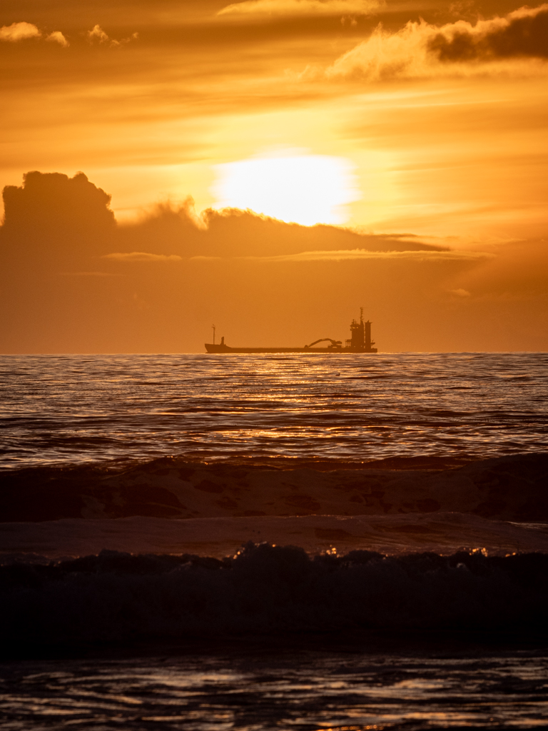 Un barco incia el rumbo hacia Europa durante la puesta de sol
