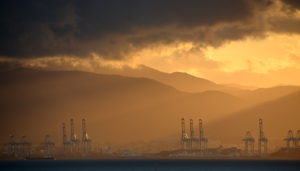 Luces del atardecer en la Bahía de Algeciras
Los rayos de sol del atardecer sobre las grúas del puerto de Algeciras, filtradas entre las nubes 
