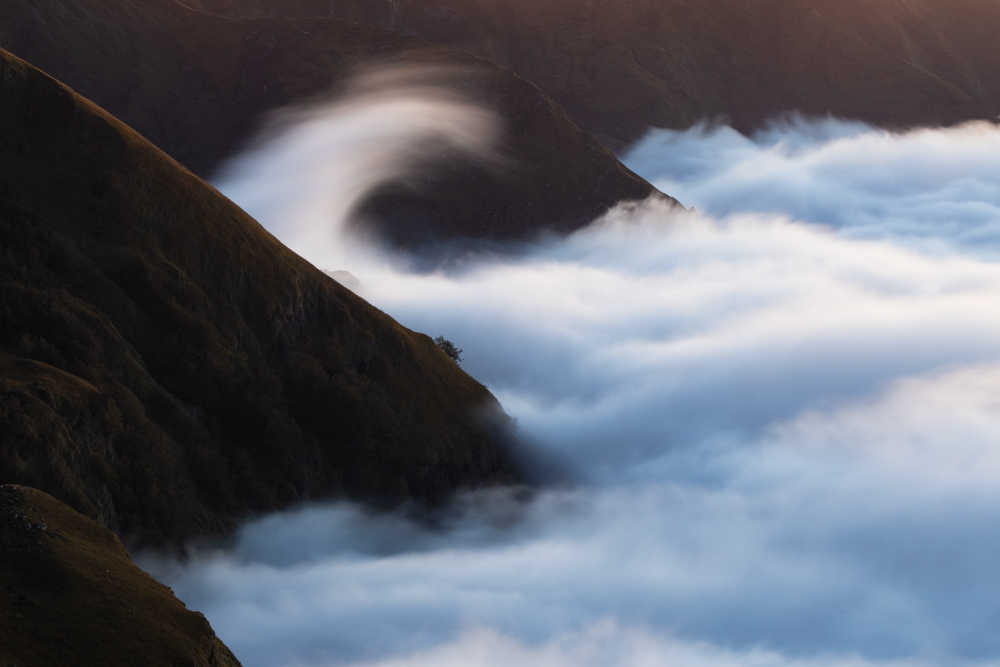 Ola de nubes
Una ola del mar de nubes rebotando contra la montaña durante el atardecer
