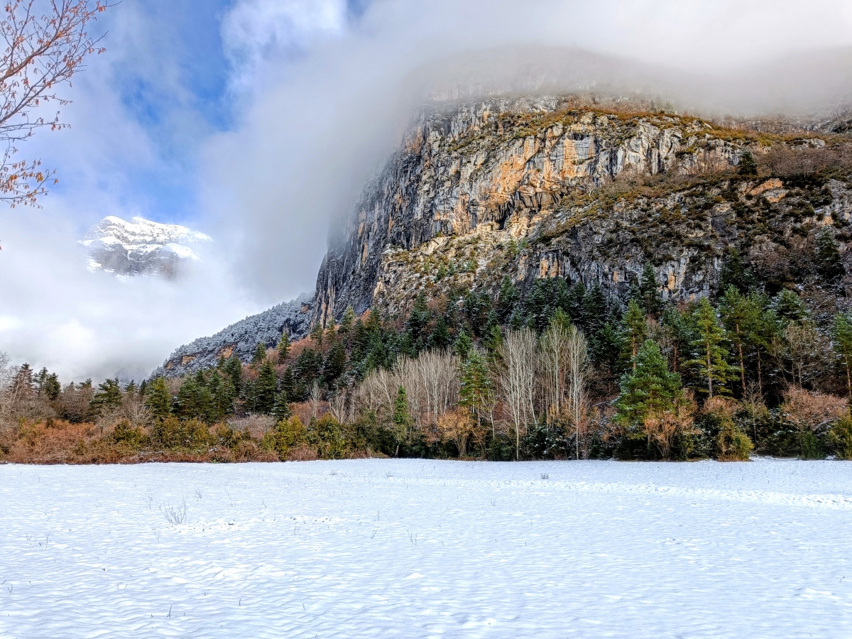 Fotografía tomada tras una nevada un par de horas antes, con restos de nubosidad pegada a las montañas y el suelo nevado.
