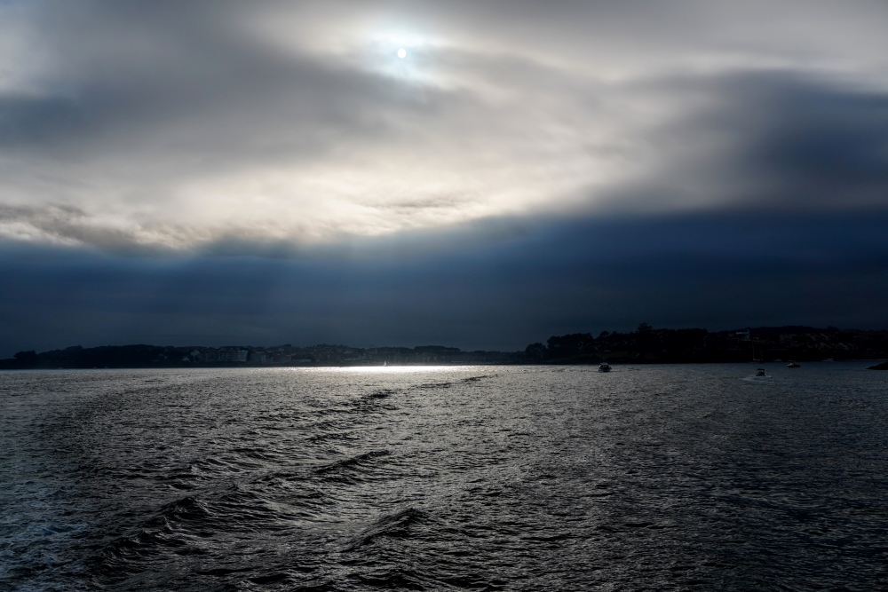 Tarde nubosa en alta mar, pero saliendo el sol al acercarse a la costa. Se observan los rayos crepusculares iluminando el mar.
