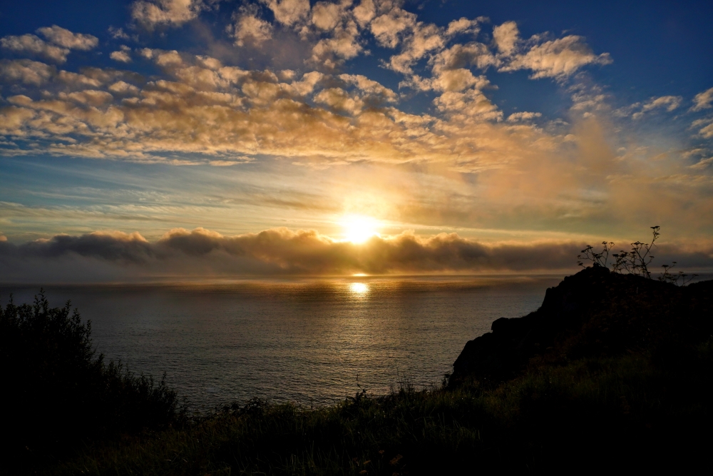 Atardecer con presencia de diversas nubes. Se observan nubes bajas en el horizonte, así como altocúmulos y cirros en el resto del cielo.
