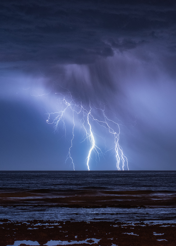 Preciosos rayos capturados en plena caza de la tormenta de noviembre en Tenerife. Con la cortina de precipitación muy visible y su reflejo en el mar. 
