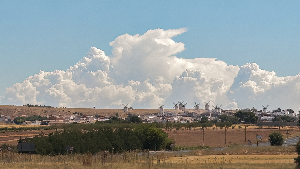 Un grupo de cumulonimbus crece por el horizonte y parece abrazar los molinos de viento.
