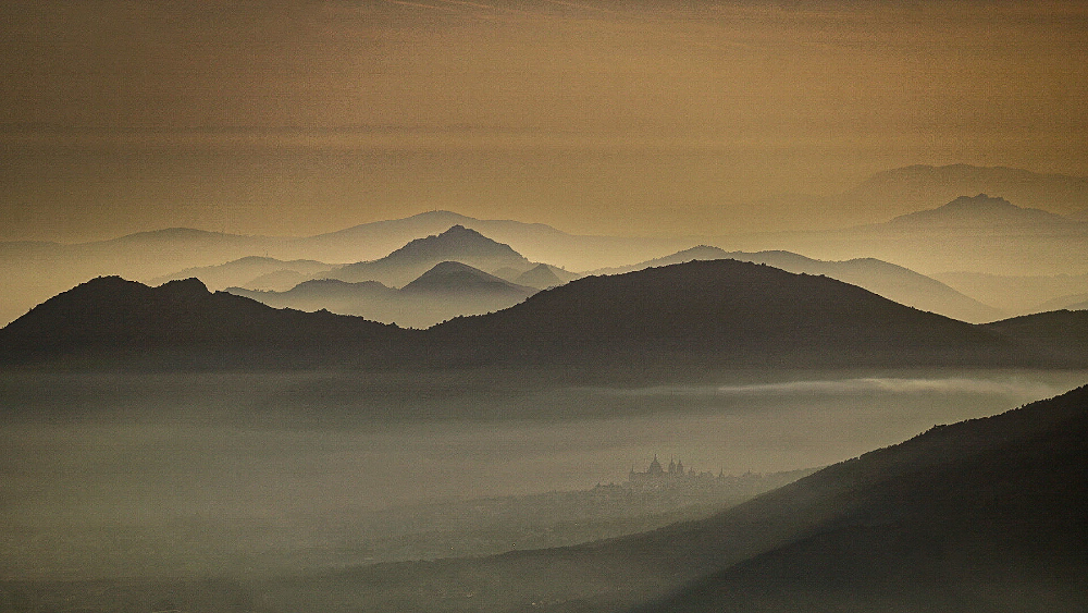 Bonitas luces y vista desde la Bola del Mundo mirando hacia el suroeste al atardecer. Se llegan a apreciar, entre la bruma, las formas del Monasterio de el Escorial
