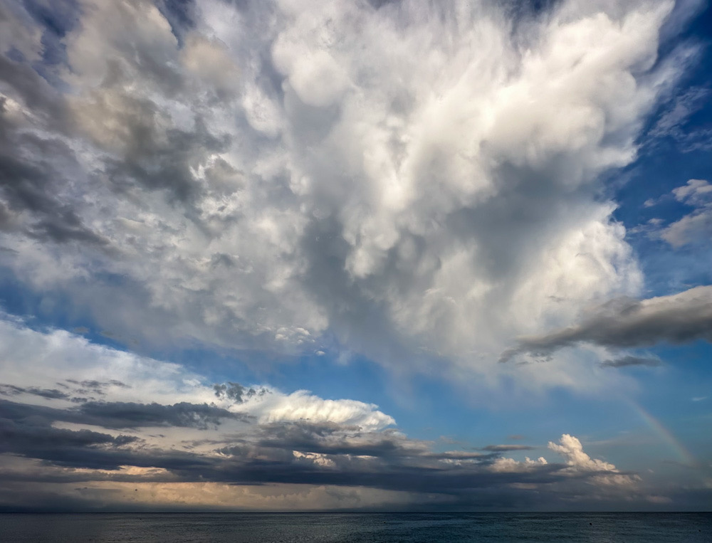 Grande cumulonimbos en el mar a la distancia y un poco de virga cerca de un arco iris a las 20:00 de la noche después del paso de la DANA. 
