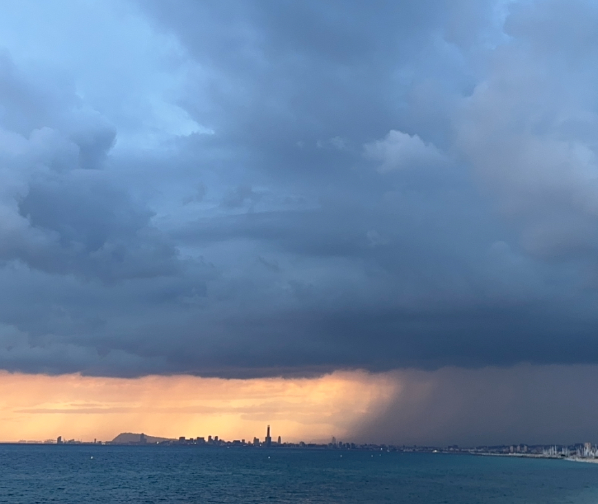 Esta foto muestra una fina cortina de lluvia en cima de barcelona en la tarde del 4 de septiembre. Había la luz del sol, la lluvia y el mar. Esta tormenta va ocurrir a la tarde del día 4 por causa de una DANA que va dejar fuertes lluvias y tormentas en partes de España este día. 
