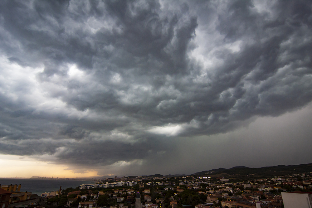 Lluvia por un lado con puesta de sol por el lado contrario con la silueta de Barcelona al fondo
