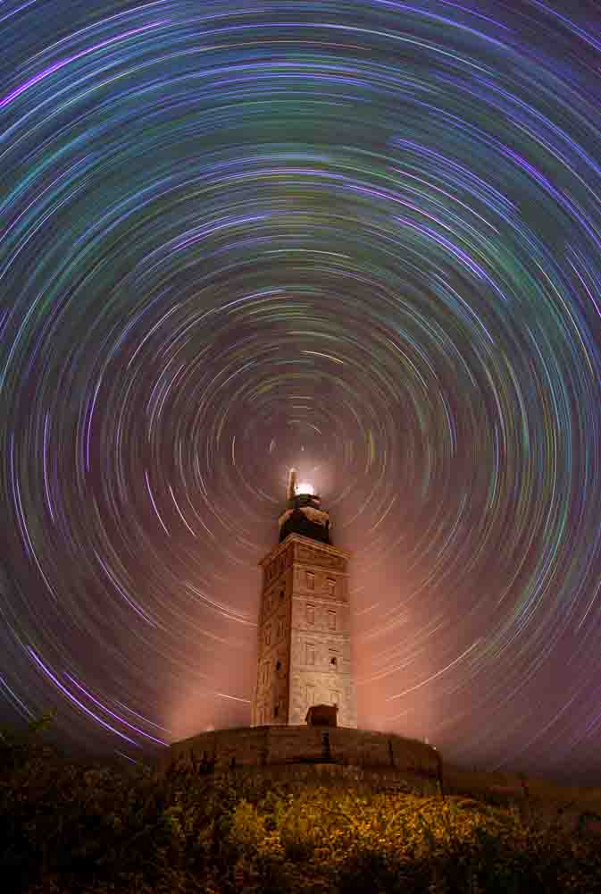 Fenómeno inusual en la Torre de Hércules, lugar caracterizado por el viento fuerte y las nubes constantes, y sin embargo te encuentras allí una noche de noviembre totalmente en calma, cielo raso y ausencia total de viento, el momento perfecto para observar las estrellas. La fotografía es un apilado de 275 fotografías para el cielo tomadas durante casi 2 horas, más un HDR para la torre y el primer plano para poder tenerla iluminada de manera uniforme, ya que la iluminación de la misma era gradual a lo largo de su altura.
