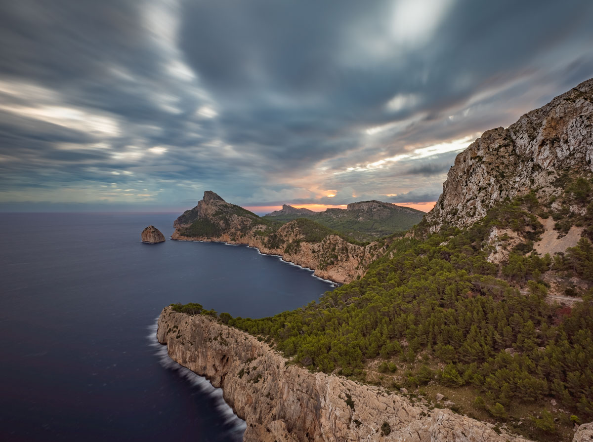 Amanecer congelado por la larga exposición, con nubes tormentosas al fondo
