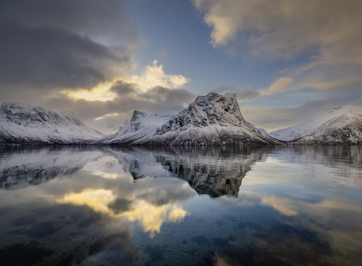 Una montaña y su reflejo matinal en el fiordo reflectante.
