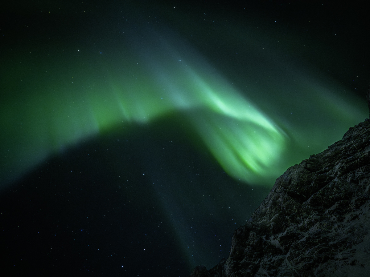 Una aurora abrazando suavemente la montaña noruega.
