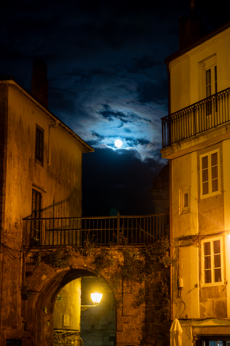 Foto de una luna azul sobre una luz naranja de Santiago de Compostela.
