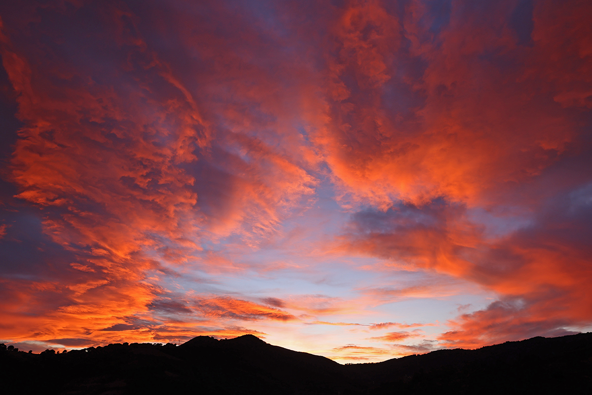 Posta de sol amb núvols de vent i cel Vermell
