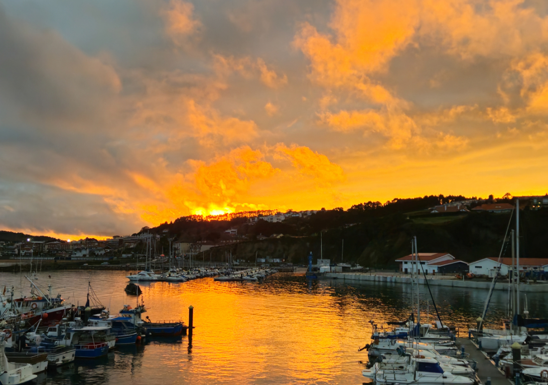 Luces, cielo y reflejos de atardecer sobre un puerto
